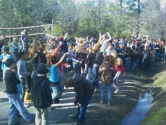 Students outside with their hands up. 